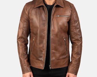May include: A brown leather jacket with a collared neckline and a zipper closure. The jacket has two side pockets and a chest pocket, all with zippers. The sleeves are long and have a tailored fit. The jacket is worn over a black shirt.