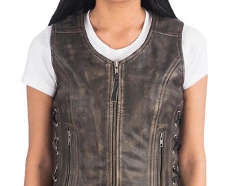 May include: A distressed brown leather vest with a zip-up front and two zippered pockets. The vest has a V-neck and lace-up detailing on the sides. The model is wearing a white t-shirt underneath.