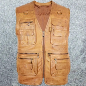 May include: A brown leather vest with multiple pockets and a zipper closure. The vest has a worn look and is made of a durable material.