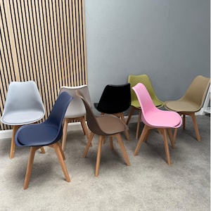 Può includere: Una collezione di sedie da pranzo moderne in vari colori, tra cui blu, grigio, nero, verde, rosa e beige. Ogni sedia ha un sedile sagomato e gambe in legno chiaro, che mostra un design minimalista.