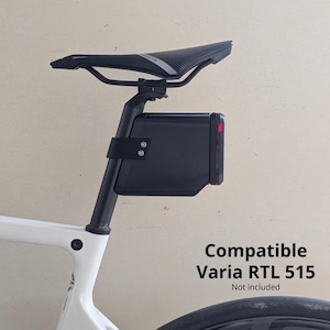 Puede incluir: Luz trasera de bicicleta negra montada en un cuadro de bicicleta blanco. La luz tiene una lente roja. El texto "Compatible Varia RTL 515" es visible. El sillín de la bicicleta es negro.