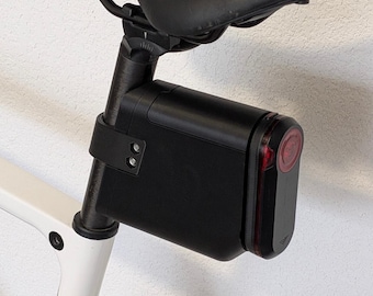 May include: A black rectangular bicycle seatpost mount attached to a round seatpost under a black saddle. The mount features a red circular light element on the rear face. Text on the image reads M Size, Varia 515 and round seatpost.