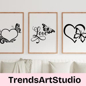 Puede incluir: Tres impresiones de arte de pared imprimibles en blanco y negro con un corazón, una mariposa y la palabra "Love" en una fuente decorativa. Las impresiones están enmarcadas en un marco de madera simple y se muestran en una pared blanca.