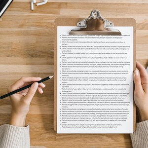 May include: A clipboard with a silver clip holds a white paper with black text. A hand holds a black pencil, poised above the paper. The text appears to be a list of observations and notes.