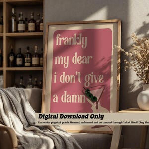 Puede incluir: Una impresión de arte imprimible rosa y blanca con el texto "francamente mi querida me importa un bledo" y una copa de martini con aceitunas. El texto está en un estilo de fuente retro. La impresión solo está disponible para descarga digital.