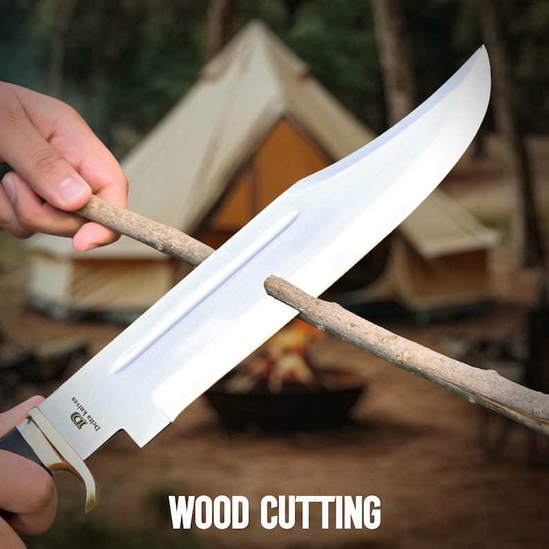 May include: A large, shiny silver knife with a black handle is being used to sharpen a wooden stick. The text "WOOD CUTTING" is displayed at the bottom of the image. A tent and campfire are in the background.