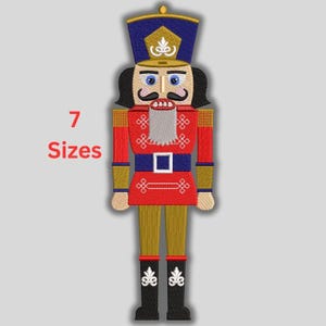 May include: Embroidered image of a traditional nutcracker soldier in red, gold, blue, and black. The nutcracker has a white beard, a blue hat, and black boots. The text "7 Sizes" is displayed in red.
