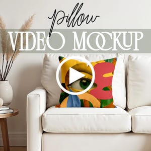 May include: A white couch with a colorful throw pillow featuring a large eye with gold makeup and a play button icon. The pillow has a yellow, red, orange, and blue design. The text "pillow video mockup" is displayed above the couch.