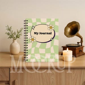 May include: A spiral-bound journal with a light green and white checkered pattern. The cover features the text "My Journal" inside an oval frame with flower and star accents. A vintage gramophone and lit candle are in the background.