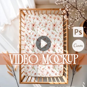 Puede incluir: Una cuna de madera con una sábana estampada con flores. La sábana presenta un fondo blanco con diseños florales rosas y verdes. Las palabras "VIDEO MOCKUP" se muestran en una fuente grande en la parte inferior de la imagen.