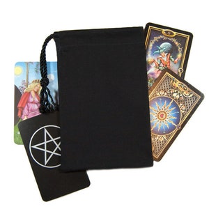 May include: A black drawstring bag with a black cord, partially obscuring several tarot cards. The cards feature colorful illustrations and symbols, including a pentagram and a sun design. The background is white.