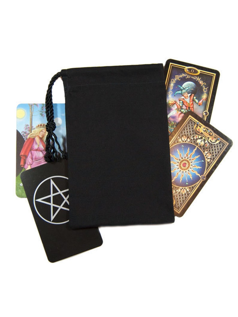 May include: A black drawstring bag with a black cord, partially obscuring several tarot cards. The cards feature colorful illustrations and symbols, including a pentagram and a sun design. The background is white.