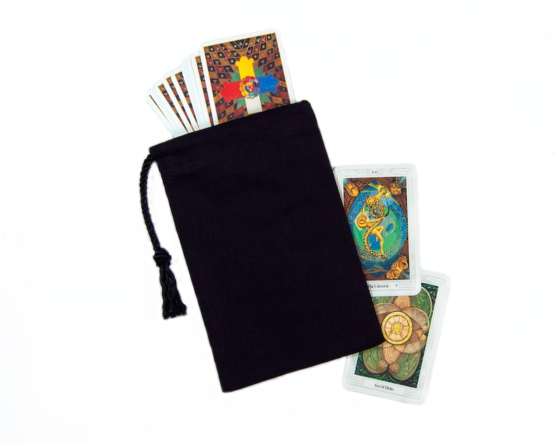 May include: A black drawstring bag with a deck of tarot cards. The cards have colorful, detailed illustrations. The bag is made of a dark fabric and has a black drawstring closure. The cards are white with colorful images.