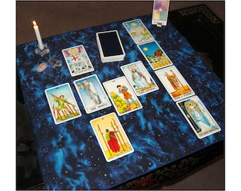 May include: A tarot card reading setup on a blue celestial patterned mat. Several tarot cards are laid out, including "The Hermit" and "Judgement". A lit white candle and a deck of cards are also present.