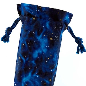 May include: A drawstring bag with a celestial design. The bag features a dark blue background with a nebula pattern and small gold stars. The drawstring is a dark blue rope. The bag is made of fabric.