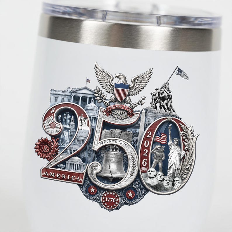 Op de afbeelding: Witte ge&iuml;soleerde beker met een zilveren rand en deksel. De beker heeft een patriottisch ontwerp met de tekst "250 AMERICA 2026" en afbeeldingen van de Amerikaanse vlag, het Vrijheidsbeeld en de Liberty Bell.
