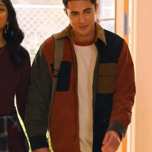 Peut inclure: Veste multicolore avec des panneaux rouges, noirs, vert olive et marron. Elle possède un col en velours côtelé et deux poches avant. Un t-shirt blanc est visible en dessous. La veste est portée sur un sac à dos.