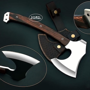May include: A hand axe with a polished silver metal head featuring a curved blade and a cutout design, paired with a dark brown wood handle secured by metal rivets. The axe includes a dark brown leather sheath with gold-coloured snap buttons.