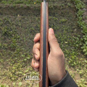 May include: A close-up of a knife with a dark blade and a brown handle. The handle has a black stripe down the center. The text "LEGION BLZ DEWORKS" is visible on the handle.