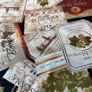 May include: A fabric print featuring a collage of vintage-style wine labels in shades of cream, brown, red, and green. The labels display text including TOSCANA, Bordeaux, and Vino blanco, alongside illustrations of grape clusters and chateaus.