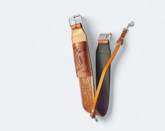 May include: Three leather straps with metal buckles and hardware. One strap is a light brown with a carved floral design. The second strap is dark green and brown. The third strap is a thin, light brown strap with a metal clasp.