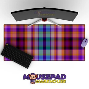 May include: A large rectangular mousepad with a colorful plaid pattern in shades of purple, orange, blue, and green. A black keyboard and a light purple mouse are on the pad. A curved monitor is above the pad.