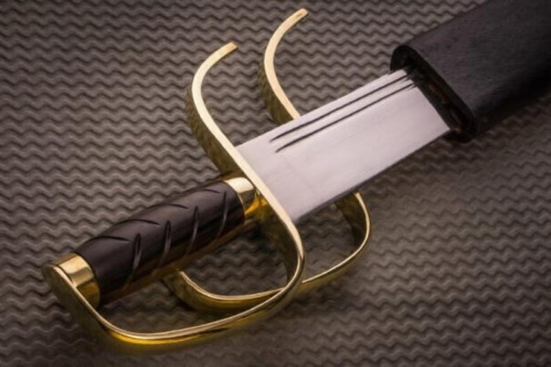 K&ouml;nnte beinhalten: Nahaufnahme eines Wing Chun Butterfly-Schwertes. Das Schwert hat eine polierte Stahlklinge, einen schwarzen Griff und einen goldfarbenen Parier. Das Schwert ist teilweise in einer schwarzen Scheide verstaut. Der Hintergrund ist eine strukturierte, dunkelgraue Oberfl&auml;che.