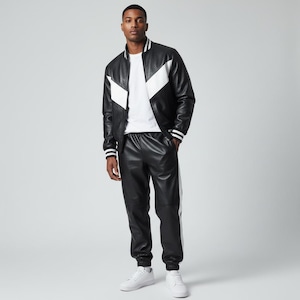 Può includere: Giacca in pelle nera con dettagli bianchi a forma di chevron e pantaloni in pelle neri abbinati con una striscia bianca. La giacca ha polsini a righe bianche e nere e un colletto bianco. L'outfit è abbinato a scarpe da ginnastica bianche.