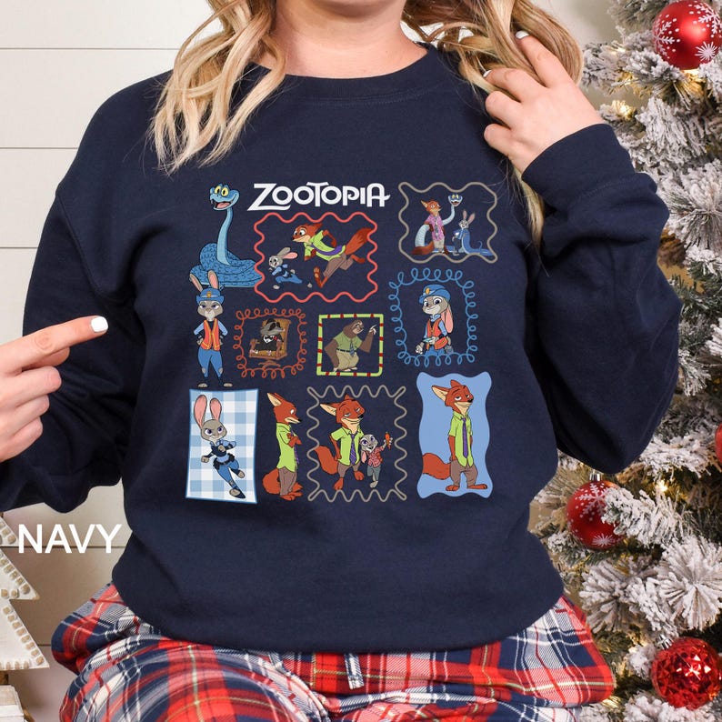 Puede incluir: Sudadera azul marino con la palabra "ZOOTOPIA" encima de nueve im&aacute;genes de dibujos animados enmarcadas de personajes de la pel&iacute;cula animada. La palabra "NAVY" est&aacute; impresa en blanco en la parte inferior izquierda de la sudadera.