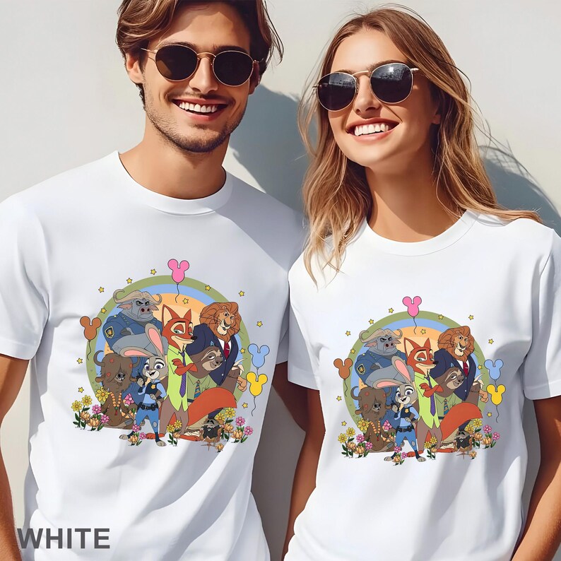 Puede incluir: Camisetas blancas con un colorido gr&aacute;fico de dibujos animados de personajes de animales. El gr&aacute;fico incluye un zorro, un le&oacute;n y otros animales, con un arco&iacute;ris y globos. La palabra "WHITE" est&aacute; impresa en la parte inferior.