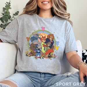Puede incluir: Camiseta gris deportiva con un gr&aacute;fico de dibujos animados de personajes de animales. El dise&ntilde;o incluye un arco&iacute;ris, globos y flores. El texto "SPORT GREY" est&aacute; impreso en la parte inferior de la camiseta.