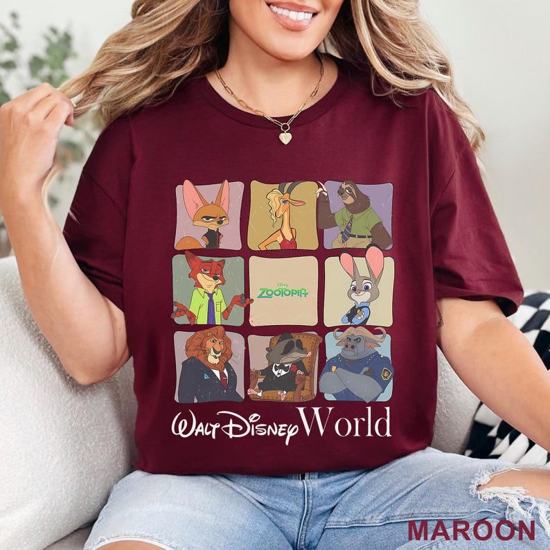 Puede incluir: Camiseta granate con un dise&ntilde;o de cuadr&iacute;cula con personajes de Zootopia. La camiseta muestra los textos "Zootopia" y "Walt Disney World" en blanco. La palabra "MAROON" est&aacute; impresa en la esquina inferior derecha.