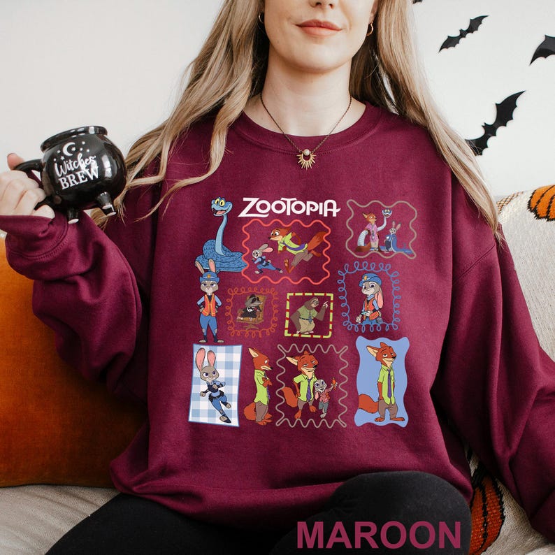 Puede incluir: Sudadera granate con un colorido collage de personajes de Zootopia en dise&ntilde;os enmarcados. La palabra "Zootopia" est&aacute; impresa en blanco en la parte superior. La palabra "MAROON" est&aacute; impresa en blanco en la parte inferior.