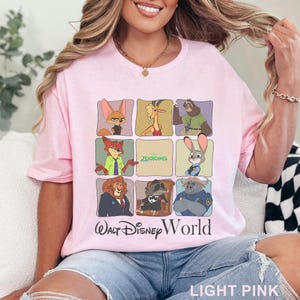 Puede incluir: Camiseta rosa claro con una cuadr&iacute;cula de personajes de Zootopia. La camiseta incluye el texto "Walt Disney World" y "Zootopia". La camiseta est&aacute; hecha de un material suave.