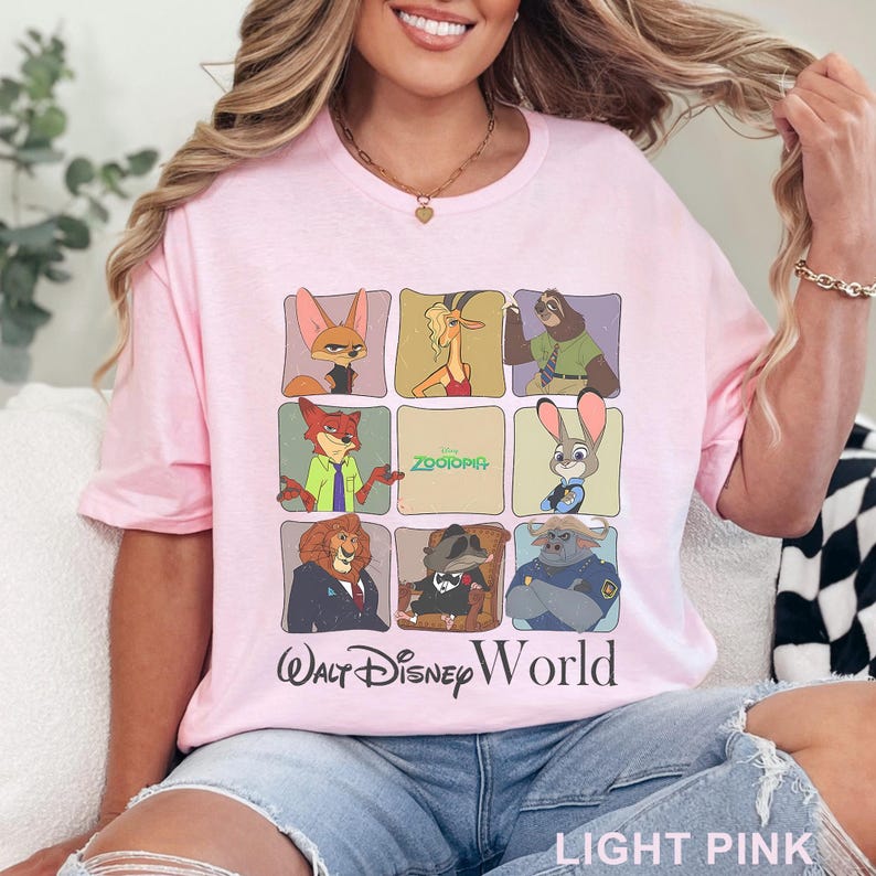 Puede incluir: Camiseta rosa claro con una cuadr&iacute;cula de personajes de Zootopia. La camiseta incluye el texto "Walt Disney World" y "Zootopia". La camiseta est&aacute; hecha de un material suave.