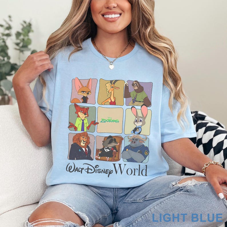 Puede incluir: Camiseta azul claro con una cuadr&iacute;cula de personajes de Zootopia. La camiseta incluye el texto "Zootopia" y "Walt Disney World" en negro. La parte inferior de la camiseta tiene las palabras "LIGHT BLUE" en blanco.