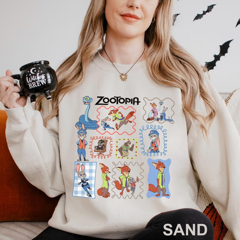 Puede incluir: Sudadera de color arena con ilustraciones de dibujos animados coloridos de personajes de la pel&iacute;cula "Zootopia". La palabra "Zootopia" est&aacute; impresa en negro. La sudadera tiene cuello redondo y mangas largas.
