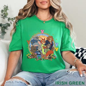 Puede incluir: Una camiseta verde con un gr&aacute;fico de dibujos animados de personajes de animales, un arco&iacute;ris, flores y globos con forma de Mickey Mouse. El texto "IRISH GREEN" est&aacute; en la parte inferior. La camiseta es de un verde vibrante.