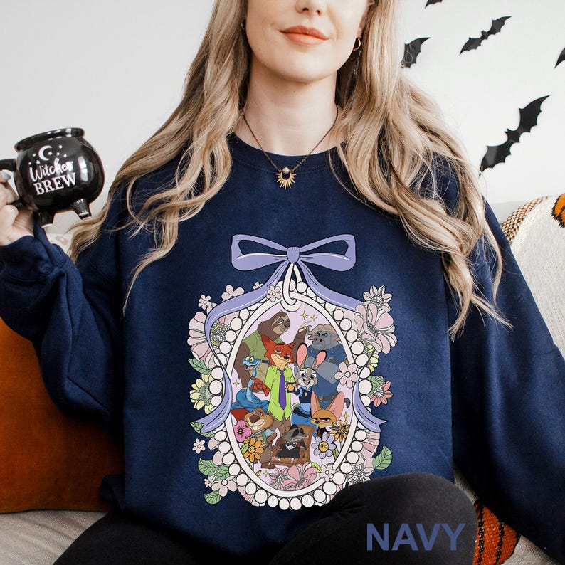 May include: Navy blue sweatshirt with a cartoon character design inside a floral frame, topped with a lavender bow. The word "NAVY" is printed at the bottom. A comfortable, casual style.