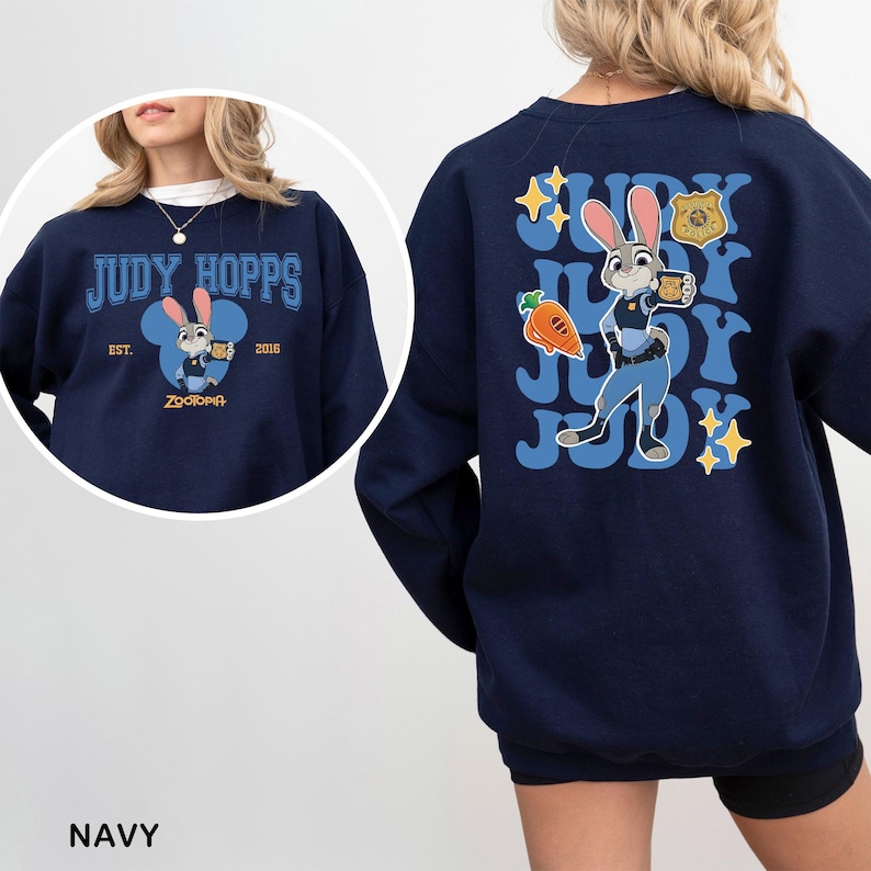 Puede incluir: Sudadera azul marino con Judy Hopps de Zootopia. El dise&ntilde;o frontal incluye el texto "JUDY HOPPS" sobre una imagen de dibujos animados de Judy. El dise&ntilde;o trasero muestra a Judy con su uniforme de polic&iacute;a, con la palabra "JUDY" repetida.