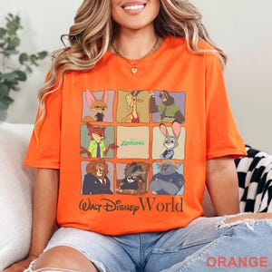 Puede incluir: Camiseta naranja con un dise&ntilde;o de cuadr&iacute;cula de personajes de Zootopia y el texto "Walt Disney World". La camiseta tiene cuello redondo y mangas cortas. Un art&iacute;culo tem&aacute;tico de Disney para fans.