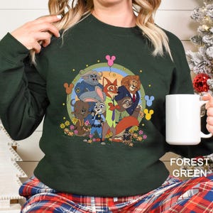 May include: Dark green sweatshirt with a cartoon illustration of animal characters, including a fox and a lion. The design is set against a rainbow and floral background. The text "FOREST GREEN" is printed at the bottom right.