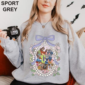 May include: Sport grey sweatshirt with a cartoon animal character design inside a floral oval frame and a light purple bow. The sweatshirt has the words "SPORT GREY" printed at the top.