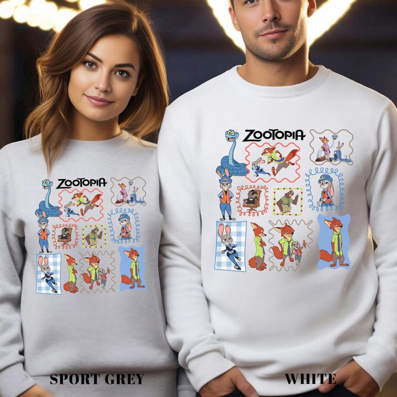 Puede incluir: Sudaderas deportivas grises y blancas con un dise&ntilde;o colorido de Zootopia. El dise&ntilde;o incluye varios personajes de la pel&iacute;cula en un estilo de sello postal. El texto "Zootopia" est&aacute; encima del dise&ntilde;o.