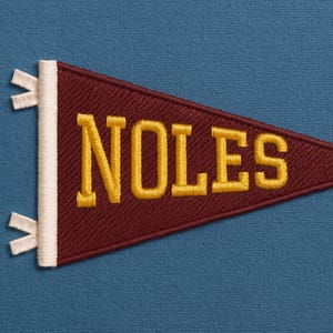 Può includere: Gagliardetto bordeaux con la scritta "NOLES" ricamata in oro. Il gagliardetto ha un bordo bianco e piccoli nastri bianchi. Lo sfondo è di colore blu uniforme. Questo articolo è probabilmente un souvenir o un articolo per tifosi.