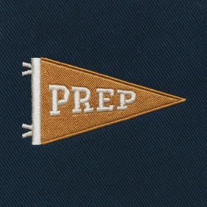 Puede incluir: Un banderín bordado en oro y blanco con la palabra "PREP" sobre un fondo azul marino. El banderín es triangular y tiene un borde blanco en el lado izquierdo. El texto está en negrita, con una fuente serif.