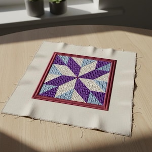 May include: A square, off-white fabric patch with a detailed embroidered quilt block design. The quilt block features a starburst pattern in shades of purple, blue, and cream, framed by a burgundy border. The fabric has raw edges.