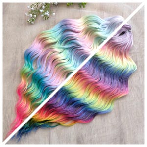 May include: A long strand of wavy, ombre hair with a rainbow colour gradient. The hair is split in half, showing the colour progression from both sides. The colours are pink, purple, blue, green, yellow, and orange.