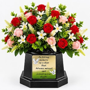 May include: A black hexagonal memorial vase filled with red and light pink roses, white flowers, and green foliage. A gold plaque on the front features two white doves and the text: In loving memory of a dear Dad. Always missed and forever in our hearts.