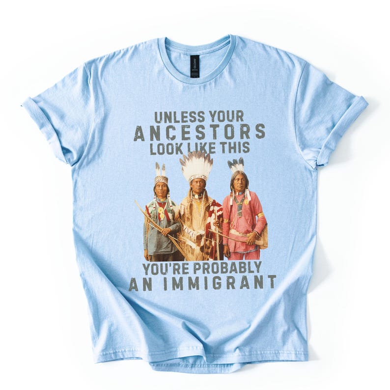 May include: Light blue t-shirt with the text "UNLESS YOUR ANCESTORS LOOK LIKE THIS YOU'RE PROBABLY AN IMMIGRANT" above a graphic of three Native American people in traditional clothing.